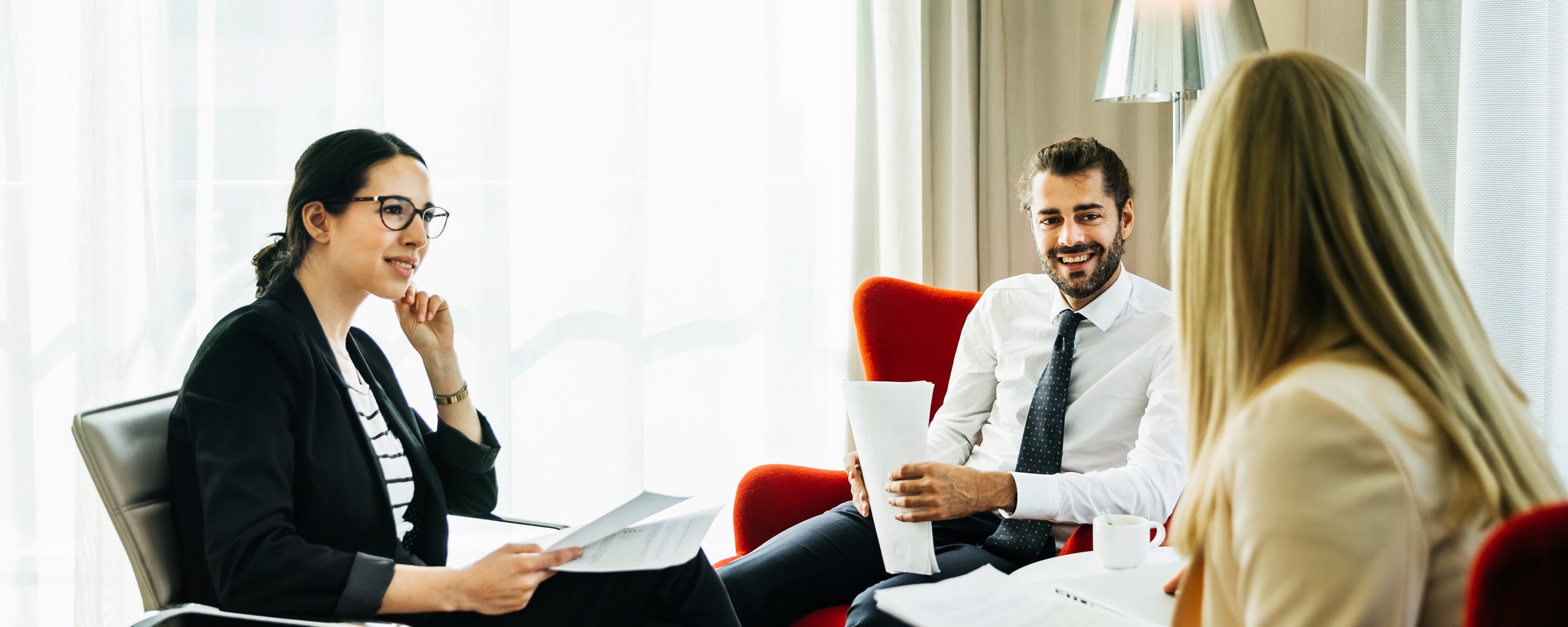 Three employees discuss business in an office setting.