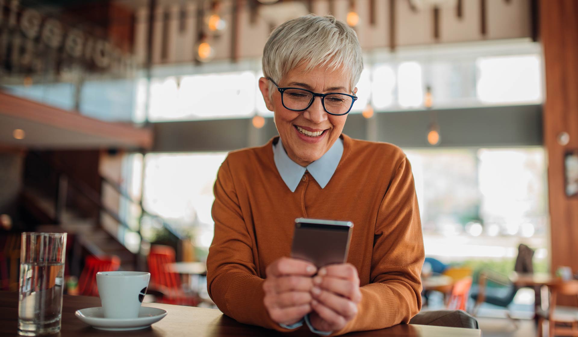 Person sitting at a coffee shop using their mobile device.