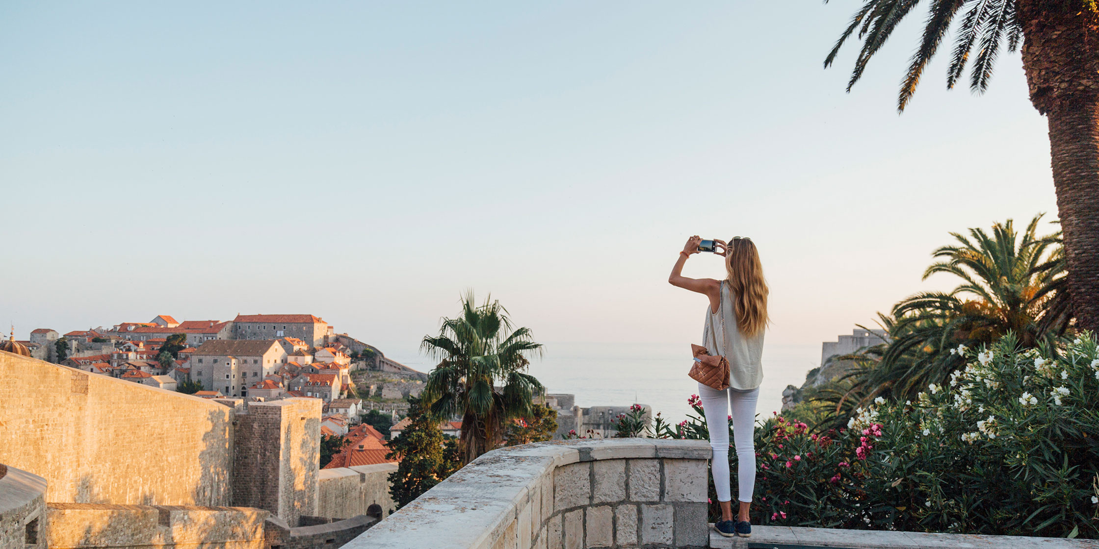 A person stands at an overlook and takes a photo of the view.