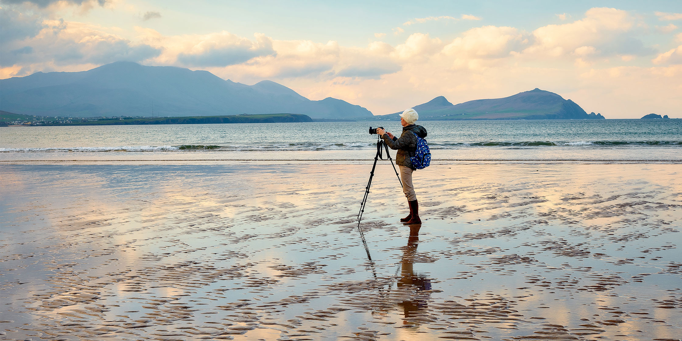 A person takes pictures on a beach during a trip they booked with their Capital One travel card.
